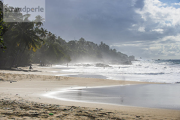 Szenische Ansicht der Wellen  die an der Küste gegen den bewölkten Himmel plätschern  in Trinidad und Tobago  Karibik