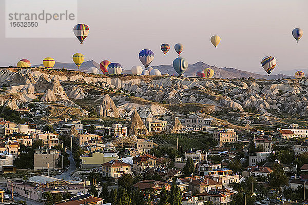 Heissluftballons fliegen über Gebäude gegen den klaren Himmel im Goreme-Nationalpark  Kappadokien  Türkei