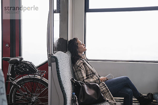 Junge Frau mit geschlossenen Augen entspannt sich in einer U-Bahn