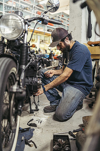 Mechaniker in einer Reparaturwerkstatt  der ein Motorrad repariert