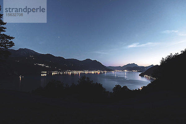 Schweiz  Gersau  Schwyz  Beleuchtete Häuser entlang der Küste des Vierwaldstättersees in der Abenddämmerung