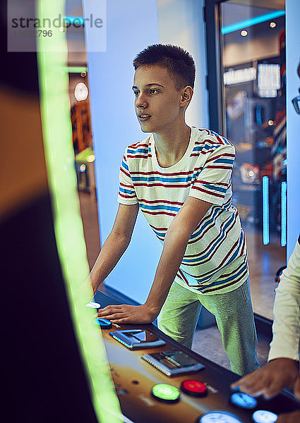 Teenager  der mit einem Spielautomaten in einer Spielhalle spielt