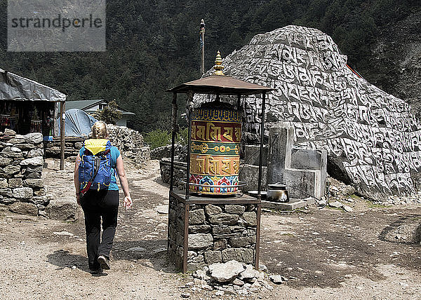 Junge Frau geht an Gebetsmühle vorbei  Manjo  Solo Khumbu  Nepal