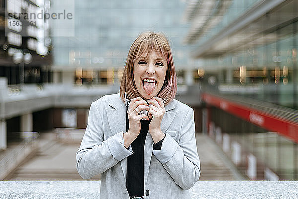 Porträt einer Frau  die in der Stadt ihre Zunge herausstreckt