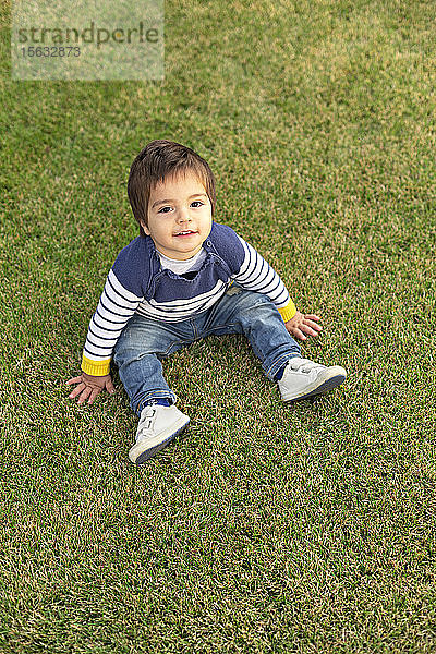 Porträt eines kleinen Jungen auf dem Rasen sitzend