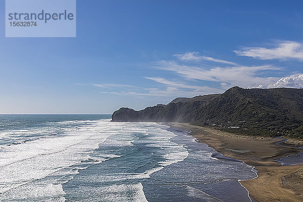 Szenenansicht einer Klippe am Meer vor blauem Himmel am Piha Beach  Auckland  Neuseeland