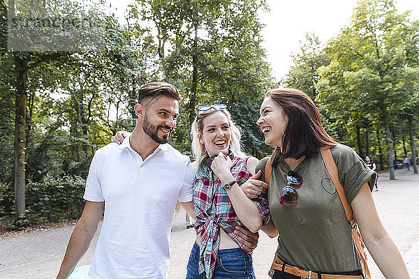 Eine Gruppe von drei Freunden spaziert zusammen in einem Park und amüsiert sich