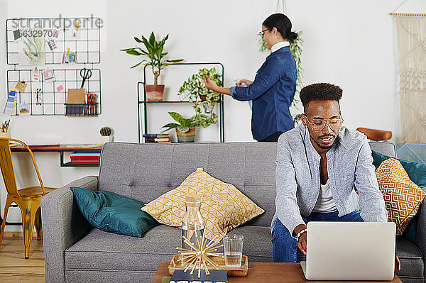 Multiethnisches Paar verbringt Zeit zusammen im Wohnzimmer  Mann benutzt Laptop