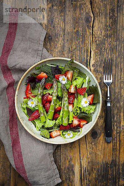 Nahaufnahme von Salat mit grünem Spargel  Erdbeeren und Gänseblümchen