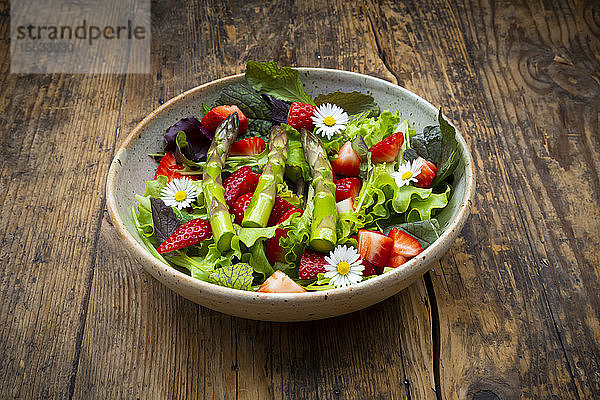 Nahaufnahme von Salat mit grünem Spargel  Erdbeeren und Gänseblümchen