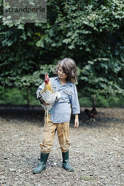 Junge mit Hühnern auf einem Biobetrieb
