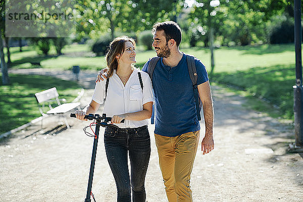 Glückliches Paar mit Elektroroller in einem Stadtpark