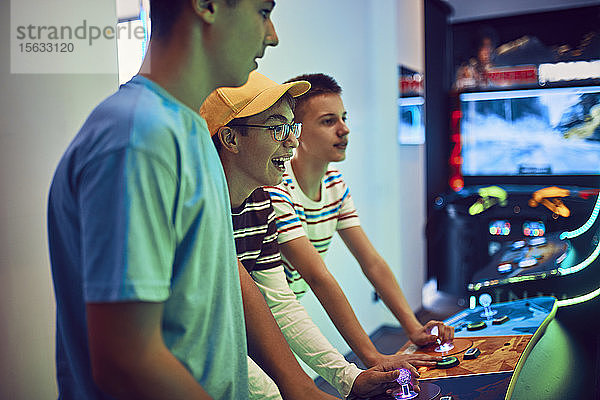 Teenager-Freunde spielen mit einem Spielautomaten in einer Spielhalle
