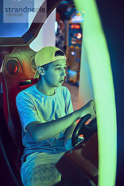 Teenager  der mit einem Fahrsimulator in einer Spielhalle spielt