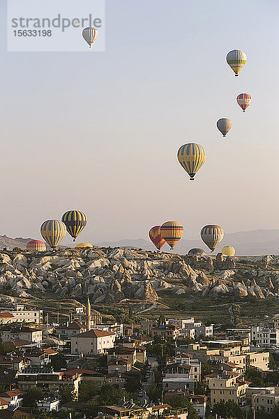 Bunte Heißluftballons fliegen über Gebäude gegen den klaren Himmel im Goreme-Nationalpark  Kappadokien  Türkei