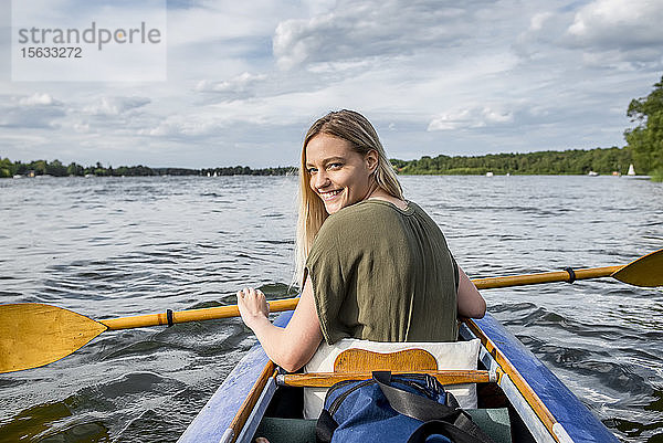Lächelnde Frau paddelt auf einem See