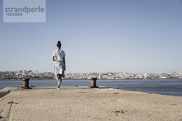 Junge Frau beim Spaziergang am Pier am Wasser  Lissabon  Portugal