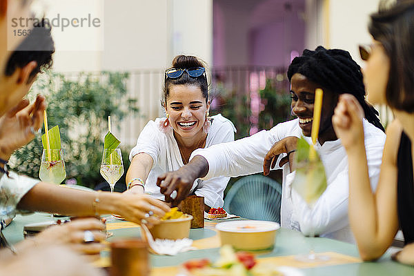Glückliche multiethnische Freunde  die sich während einer Party amüsieren  zusammen essen