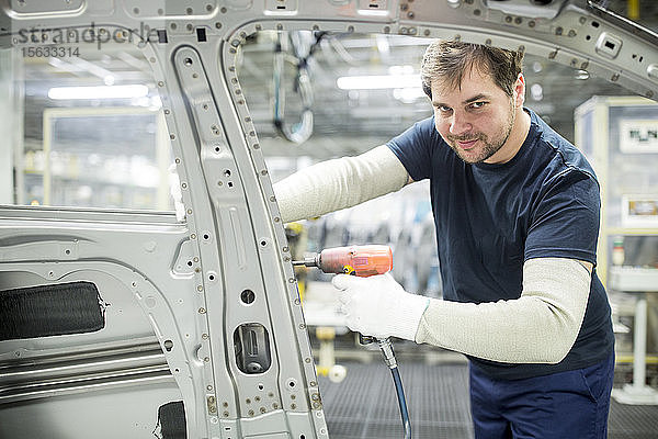 Porträt eines selbstbewussten Mannes  der in einer modernen Autofabrik arbeitet