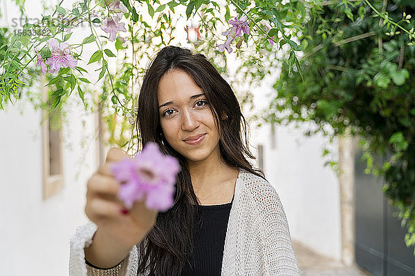 Porträt einer jungen Frau mit rosa Blume