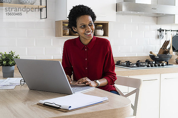 Lächelnde junge Frau benutzt Laptop zu Hause