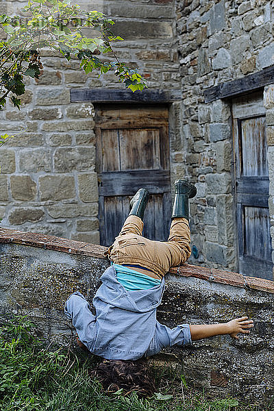 Verspielter Junge beim Kopfstand in einem rustikalen Bauernhaus