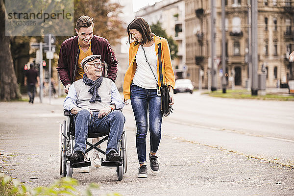 Glücklicher älterer Mann im Rollstuhl  der Zeit mit seinen Enkelkindern verbringt