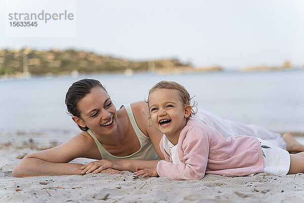 Glückliche Mutter mit Tochter am Strand liegend