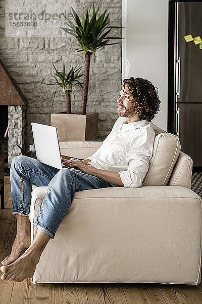 Mann benutzt Laptop zu Hause auf der Couch