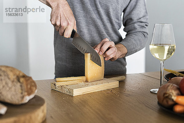 Nahaufnahme eines Mannes  der Käse auf der Küchentheke schneidet