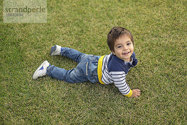 Porträt eines lächelnden kleinen Jungen auf dem Rasen liegend