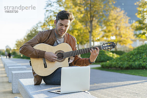 Mann mit Laptop spielt Gitarre in der Stadt  Madrid  Spanien