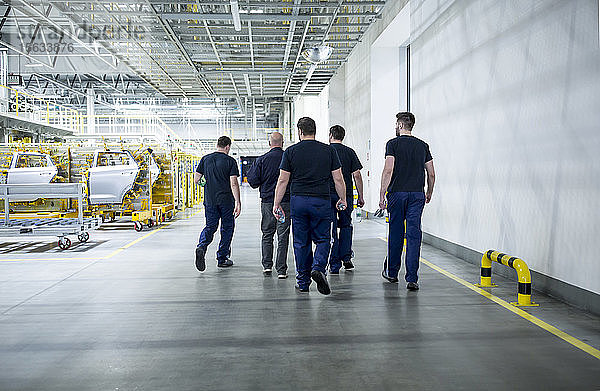 Kollegen machen eine Pause und spazieren in einer modernen Autofabrik