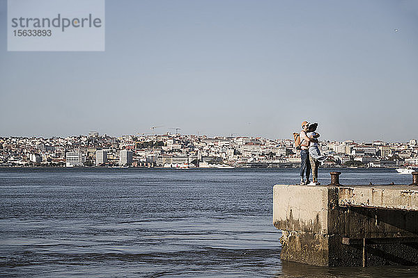 Junges Paar umarmt sich am Pier am Wasser  Lissabon  Portugal