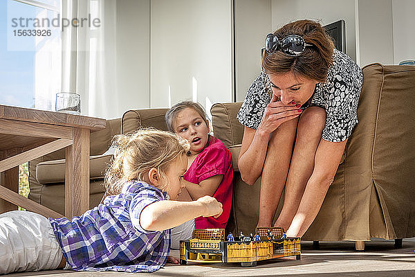 Mutter spielt mit Töchtern im Wohnzimmer