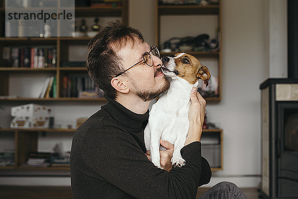 Junger Mann mit Jack Russel Terrier  leckend