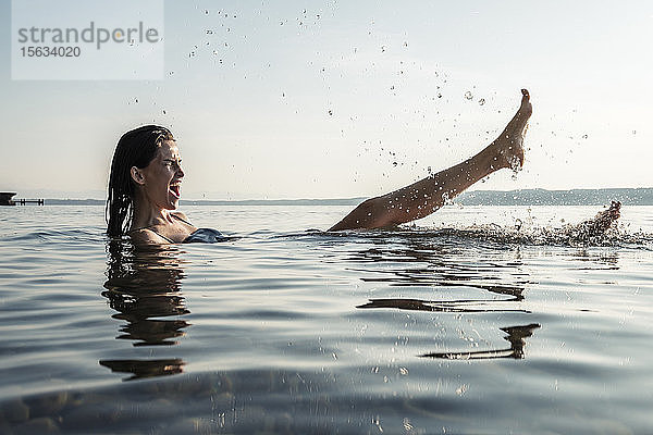 Junge Frau badet im Starnberger See und planscht mit Wasser  Deutschland