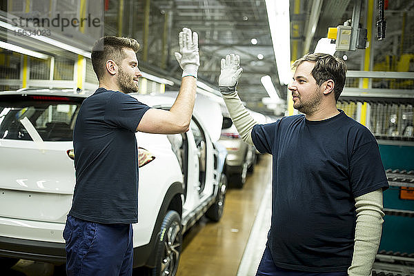 Zwei Kollegen geben sich in moderner Autofabrik die Klinke in die Hand