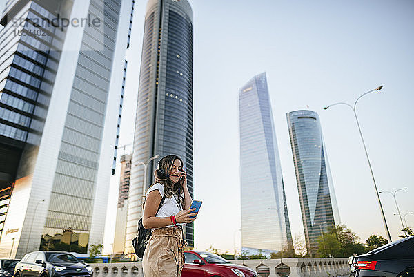 Junge Frau benutzt ein Smartphone mit Wolkenkratzern im Hintergrund