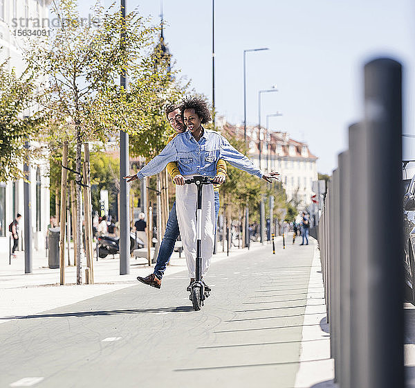 Glückliches junges Paar fährt E-Scooter in der Stadt