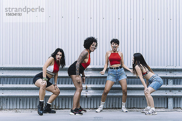 Vier junge sexy Tänzer tanzen auf einer Strett vor einer Wand