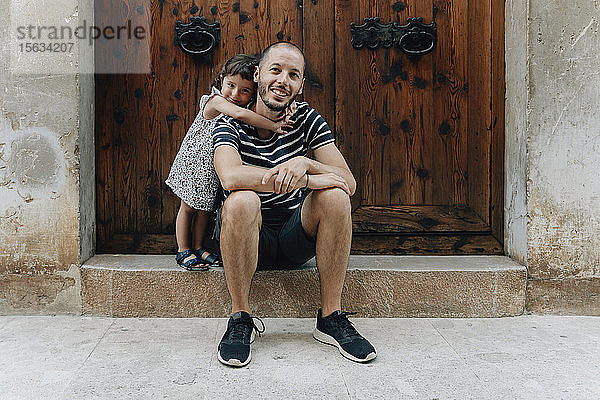 Porträt eines glücklichen kleinen Mädchens  das seinen Vater im Freien umarmt  Mallorca  Spanien