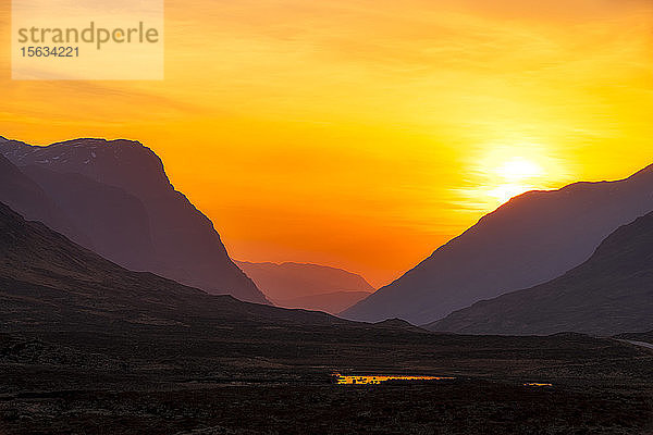 Landschaftliche Ansicht der Berge vor orangefarbenem Himmel in Glencoe  Highlands  Schottland  Großbritannien