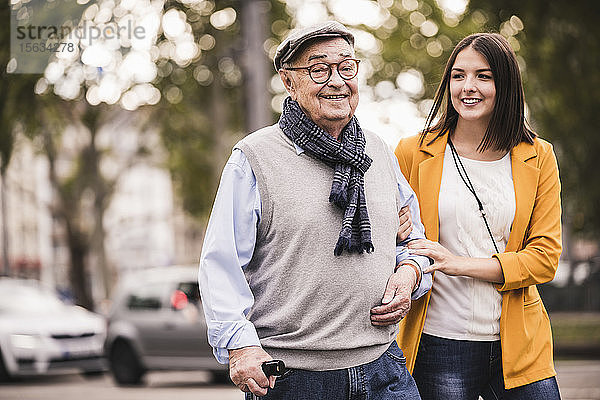 Porträt eines älteren Mannes  der zusammen mit seiner erwachsenen Enkelin spazieren geht
