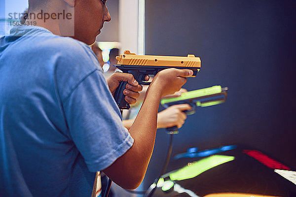 Teenager-Freunde schießen mit Pistolen in einer Spielhalle