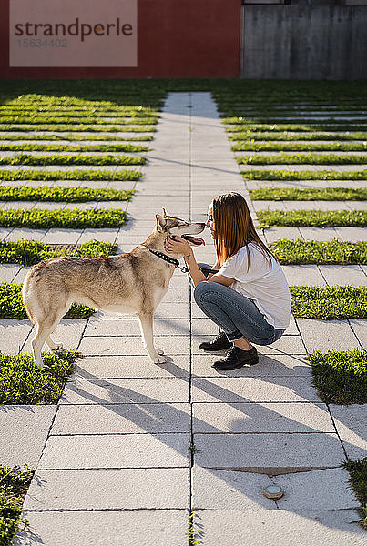 Junge Frau kuschelt mit ihrem Hund im Freien