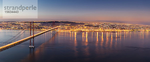 25. April Brücke über den Tejo vor beleuchteter Stadtlandschaft in der Abenddämmerung  Lissabon  Portugal