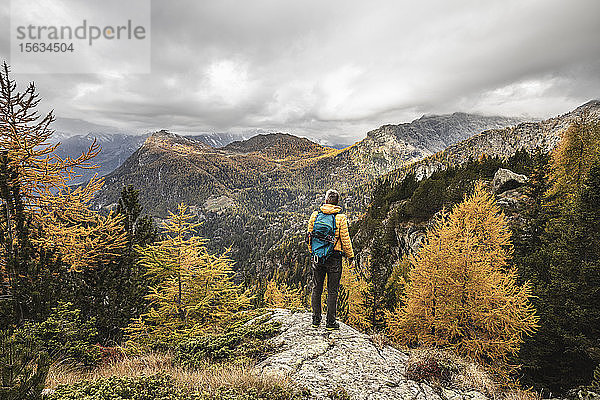 Wanderer steht und blickt im Herbst über das Alpenplateau  Sondrio  Italien