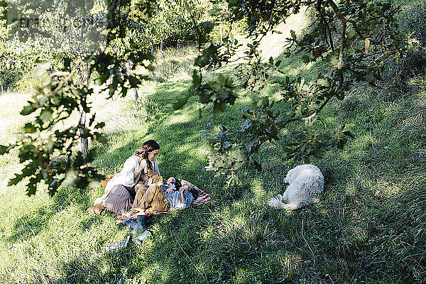 Mutter mit zwei Kindern und Hund entspannt sich auf dem Land