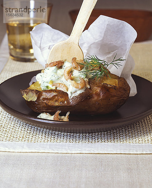 Nahaufnahme einer Folienkartoffel mit Krabben und saurer Sahne  serviert in einem Teller auf dem Tisch